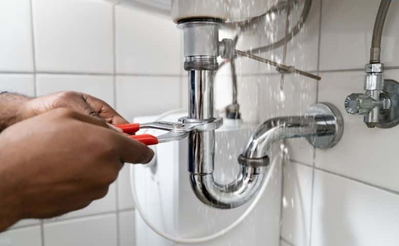 Plumber Fixing a Bathroom Leak Under the Sink.